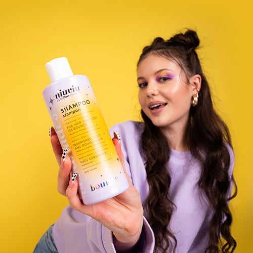 niuviu Bounce szampon z żółtym opakowaniem, kobieta w liliowej bluzie na żółtym tle