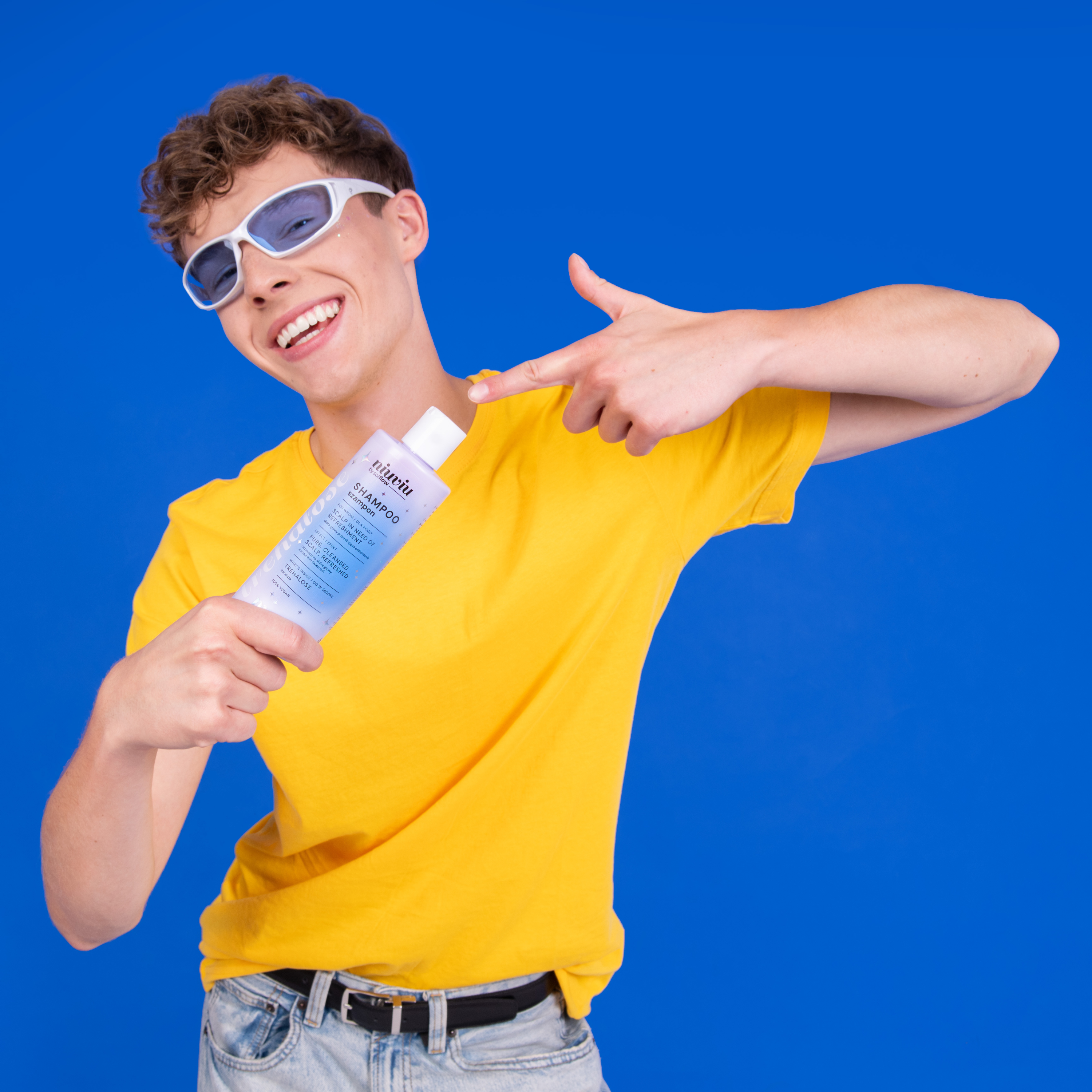 niuviu Pure szampon w niebieskim opakowaniu, trzymany przez osobę w żółtej koszulce